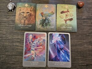 Five oracle cards displayed on a wooden surface, featuring Bobcat Spirit, Grasshopper Spirit, Ant Spirit, Trusting in Destiny, and Loving the Self on All Levels, surrounded by small crystals and a “Be Fearless” charm