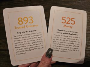 Two angel number oracle cards, 893 and 525, offering guidance on trusting the universe and allowing abundance to flow