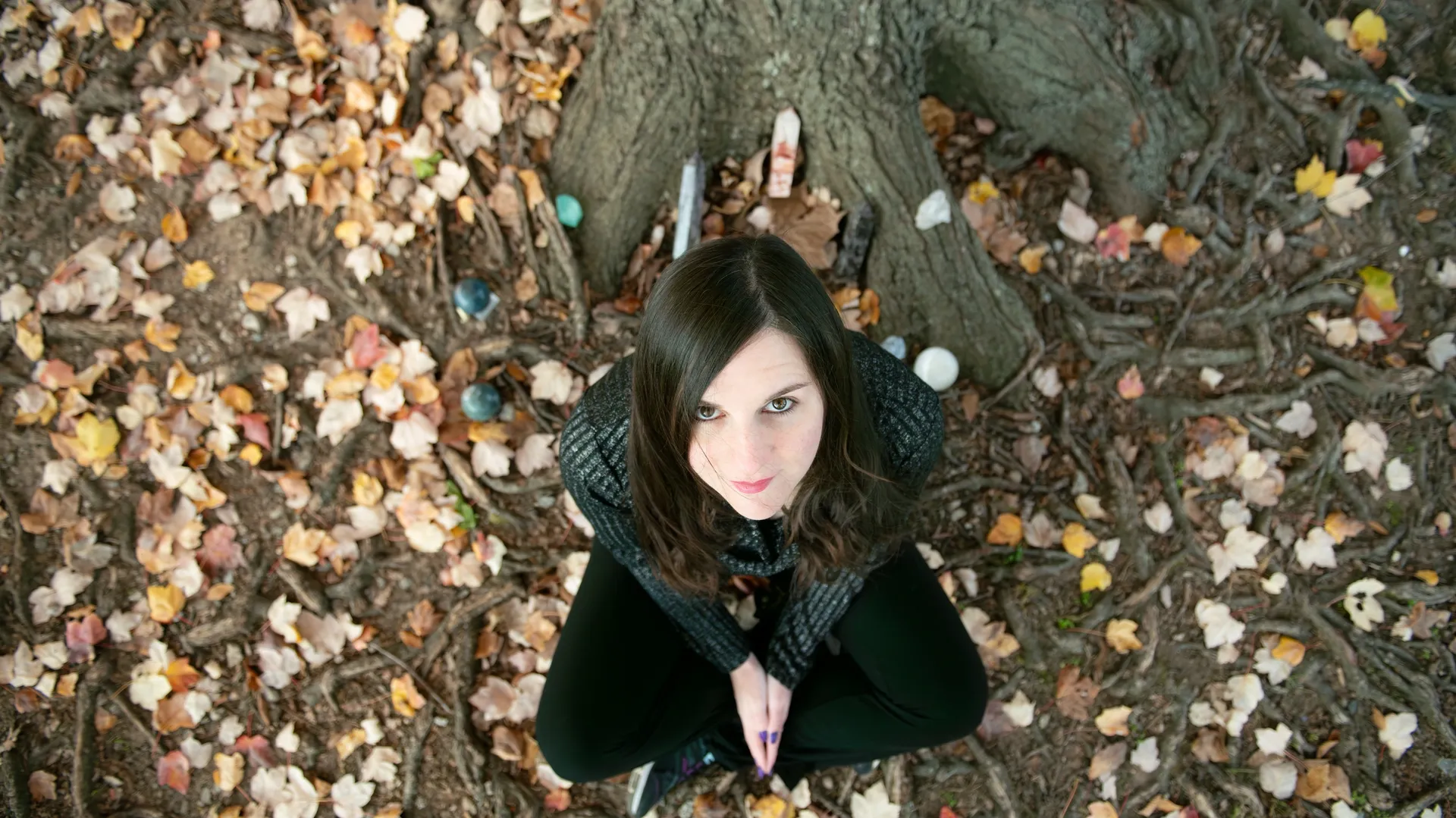 Spiritual healer seated at the base of a tree preparing for private energetic space cleansing